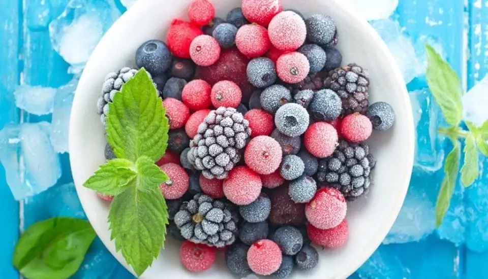 Frozen berries in a bowl on a blue background.