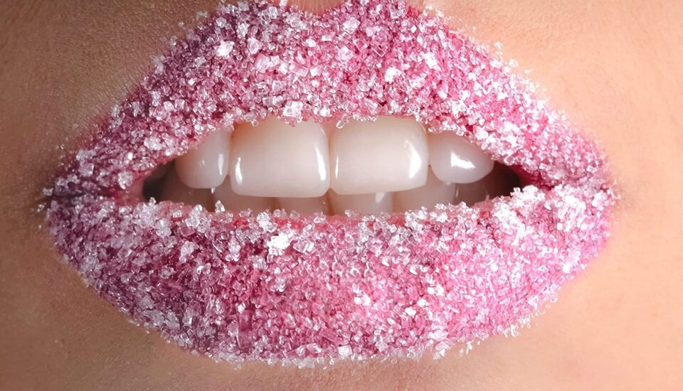 A close up of a woman's lips covered in pink sugar.