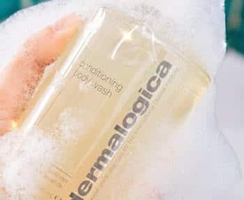 A person holding a bottle of Dermalogica cleansing foam.